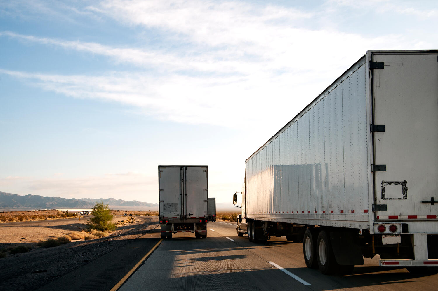 Two semi trucks driving on highway
